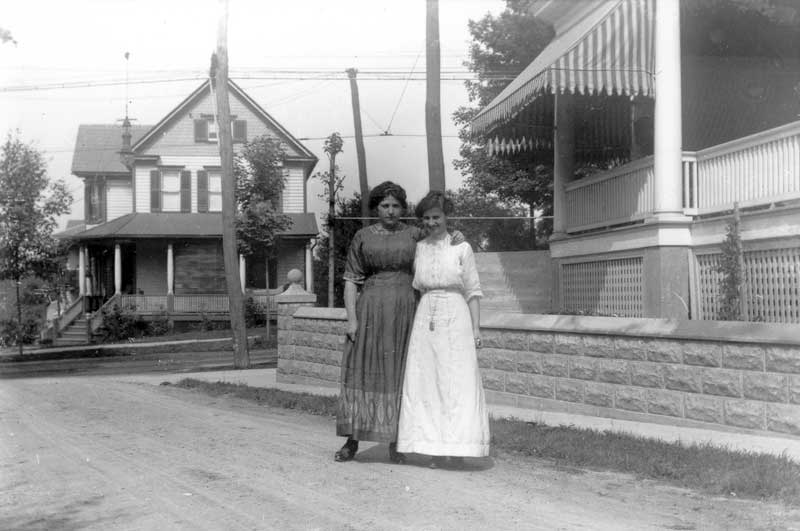 Two women standing on Dearr Street in East Stroudsburg with their backs to the Sam Scott house at 152 N. Courtland St., circa 1912.